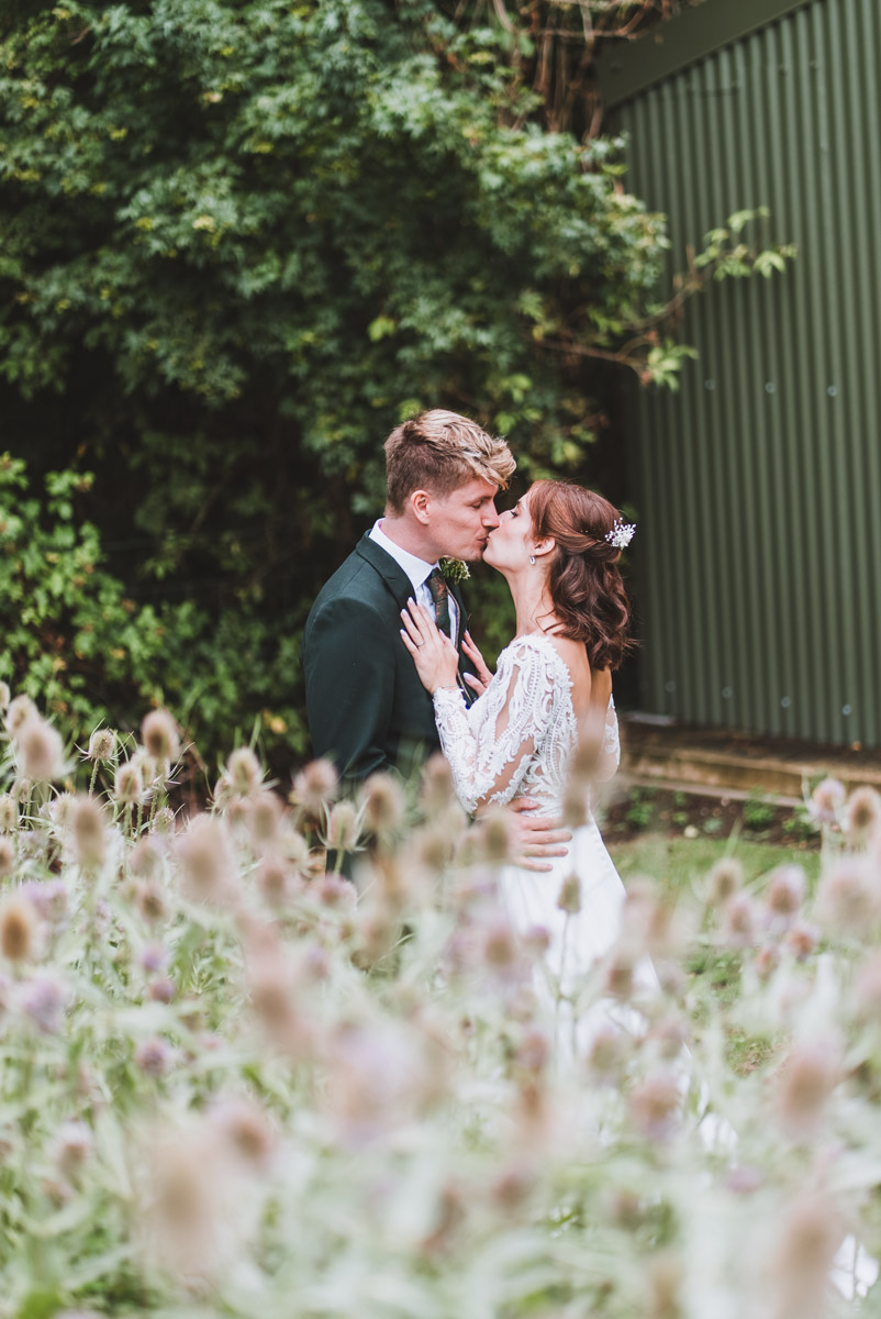Loves first kiss of bride and groom in the wild flowers