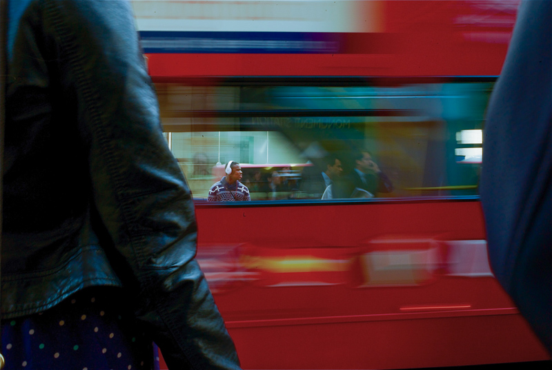 Red London bus passing a crossing with man seen through the window