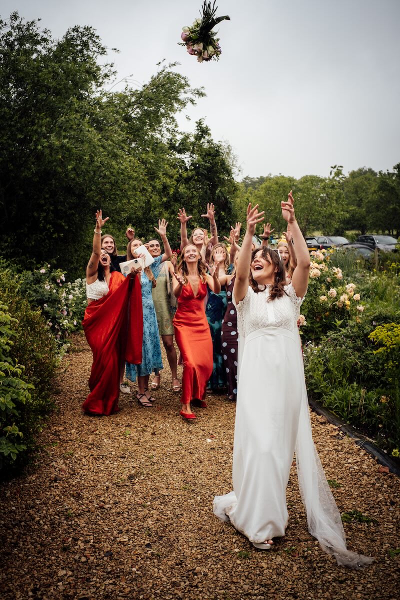 Roo throwing her wedding bouquet to guests at Worton Kitchen Garden
