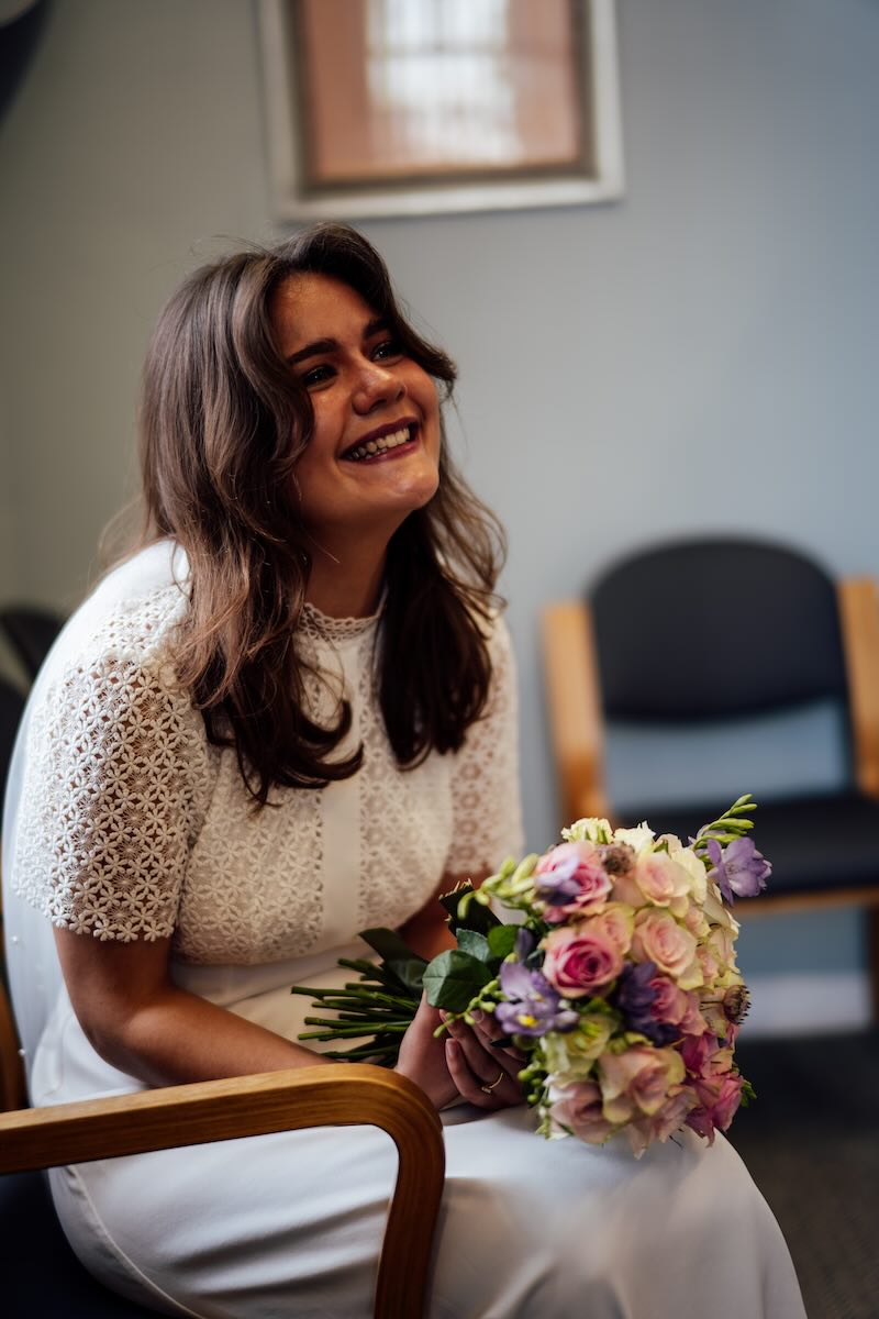 Roo smiling with her wedding bouquet inside Oxford Registry Office